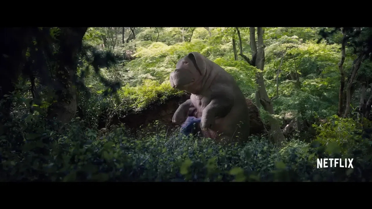 Una niña junto a un enorme cerdo gris en un bosque, fotograma del tráiler de Okja